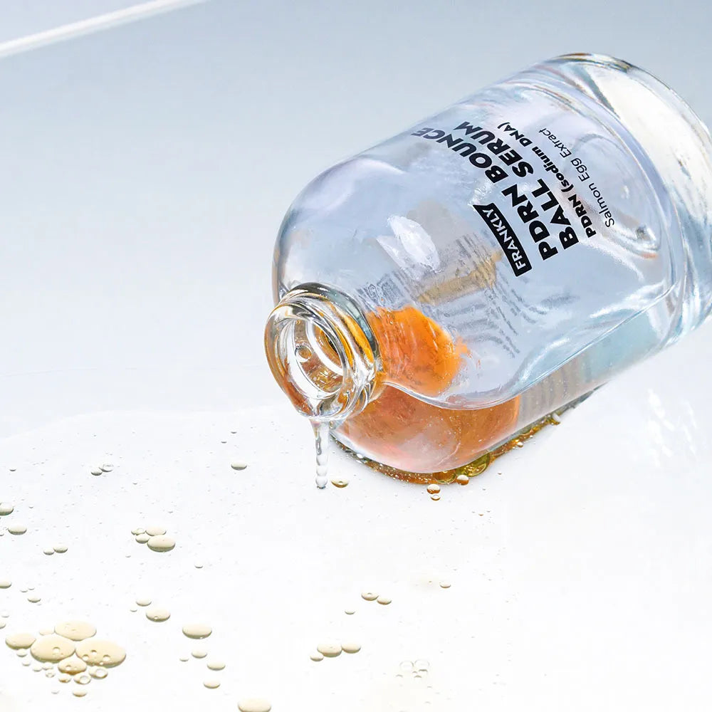 Innovative dual-layer texture of FRANKLY PDRN Serum showing the orange oil capsules blending into a clear watery essence at Atelier De Glow UK.
